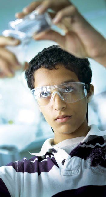 A young man wearing safety goggles is holding something in his hands