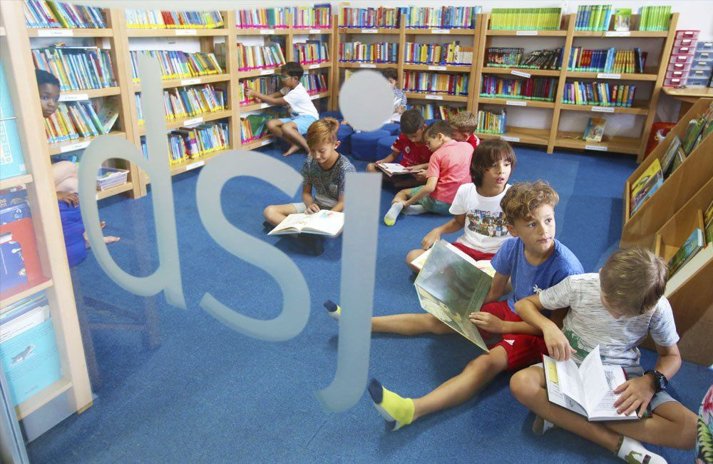 A group of children are sitting on the floor in a library reading books