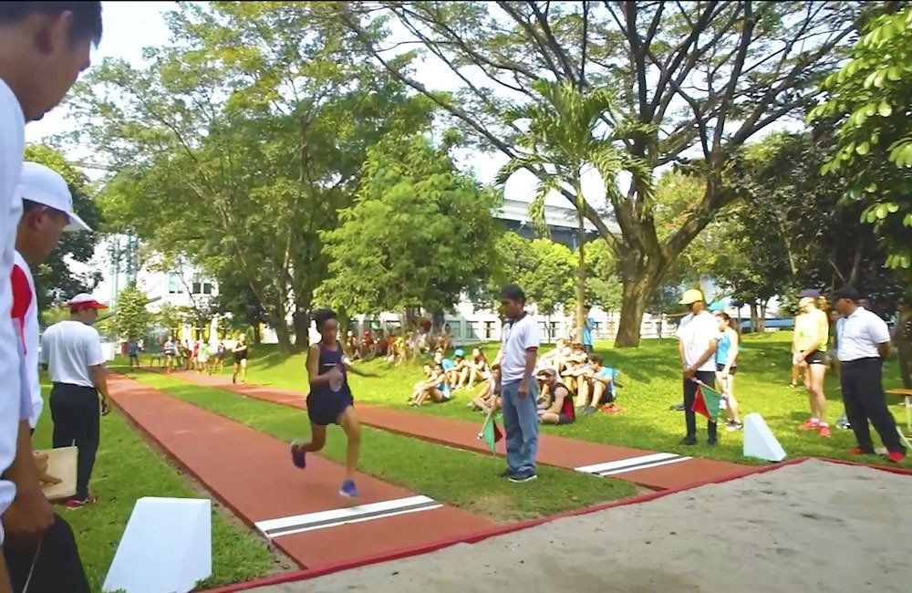 A group of people are standing around a track in a park.