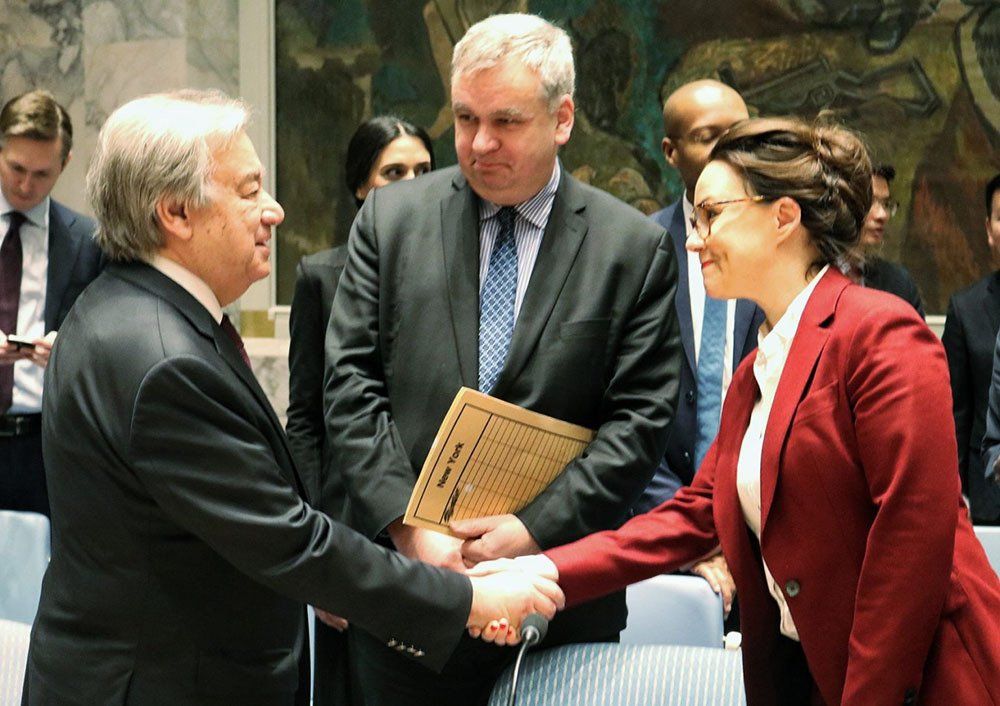 A woman in a red jacket is shaking hands with a man in a suit.