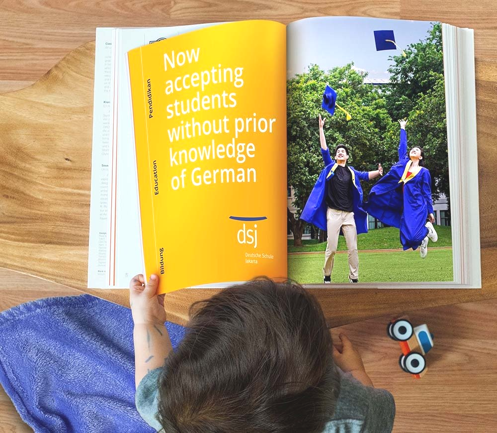 A child is reading a book that says now accepting students without prior knowledge of german