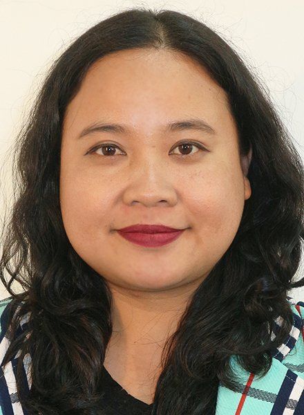 A woman with long dark hair and red lipstick is smiling for the camera.