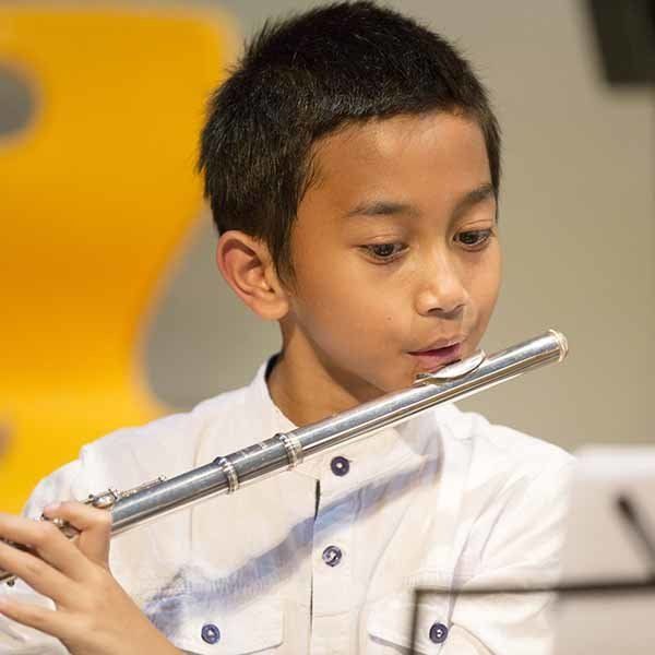A young boy is playing a flute on a stage.