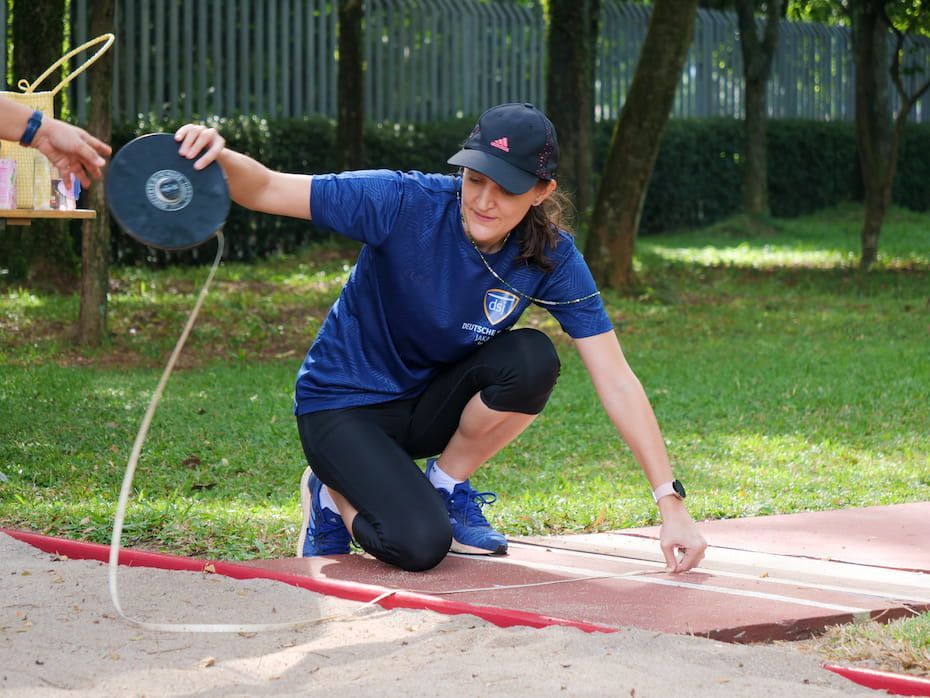 A woman in a blue shirt is kneeling down on a track