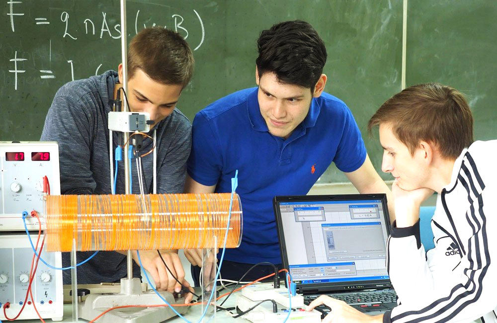 A group of young men are working on a project in front of a blackboard.
