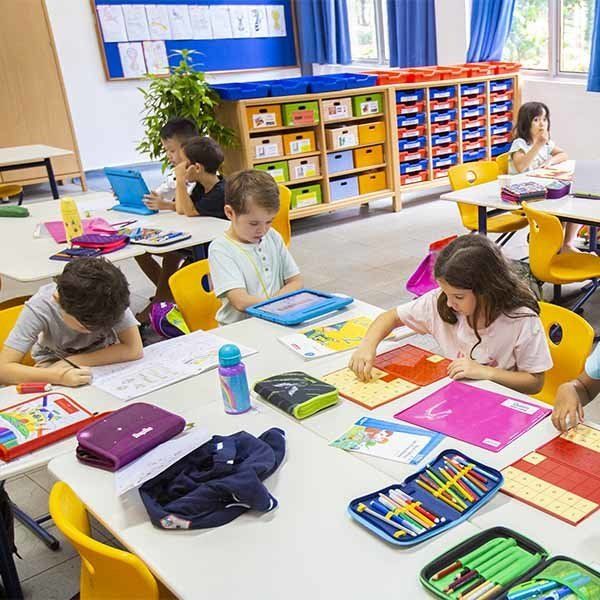 A group of children are sitting at tables in a classroom.