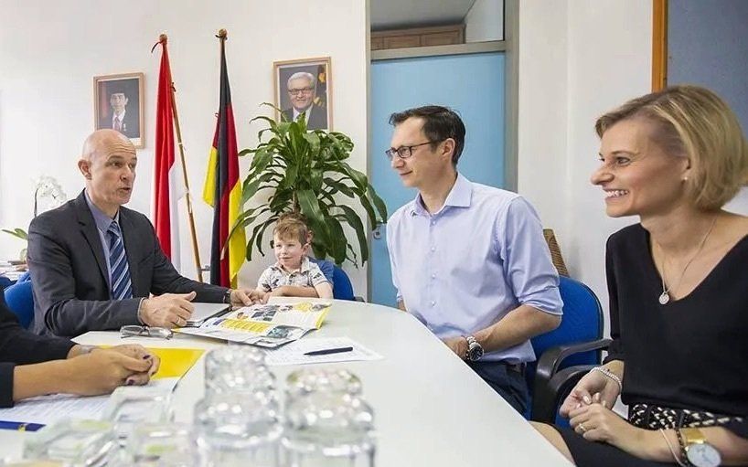 A group of people are sitting around a table having a meeting.