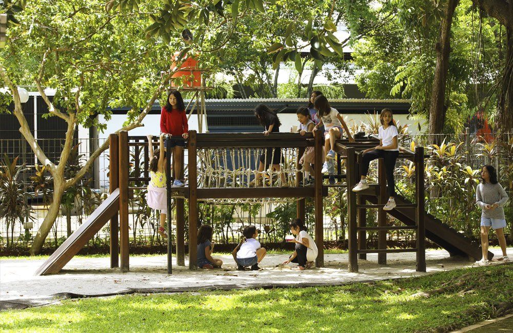 A group of children are playing on a wooden playground in a park.