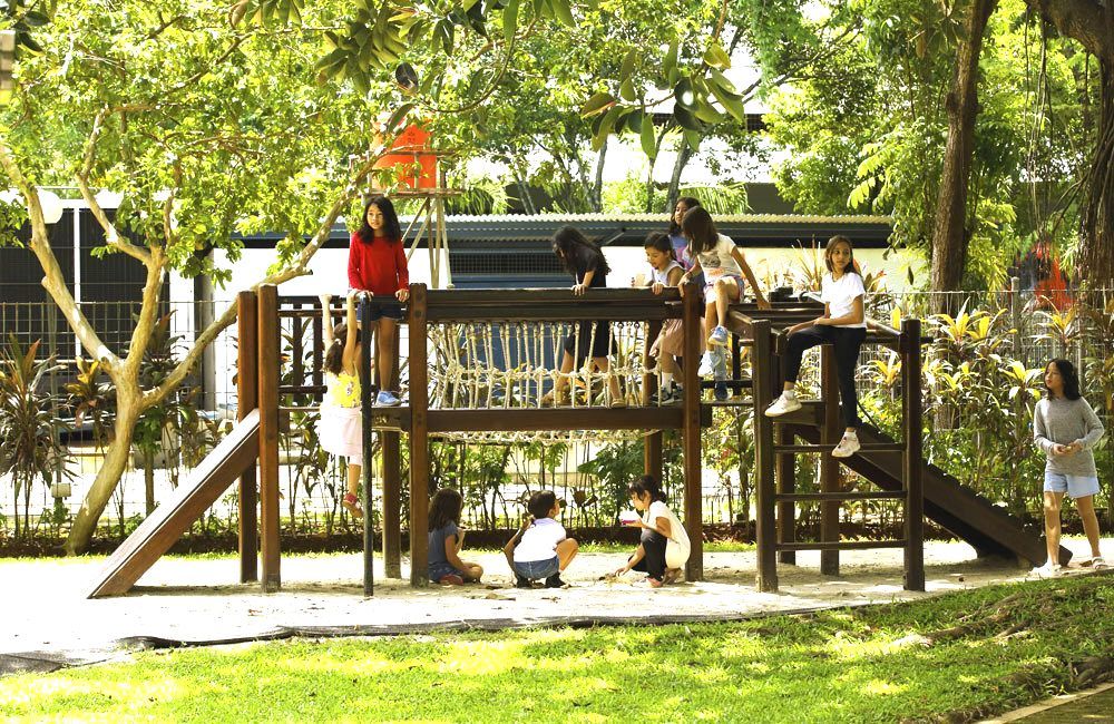 A group of children are playing on a wooden playground in a park.