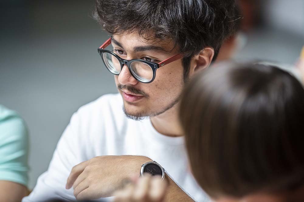 A man wearing glasses is talking to a woman.