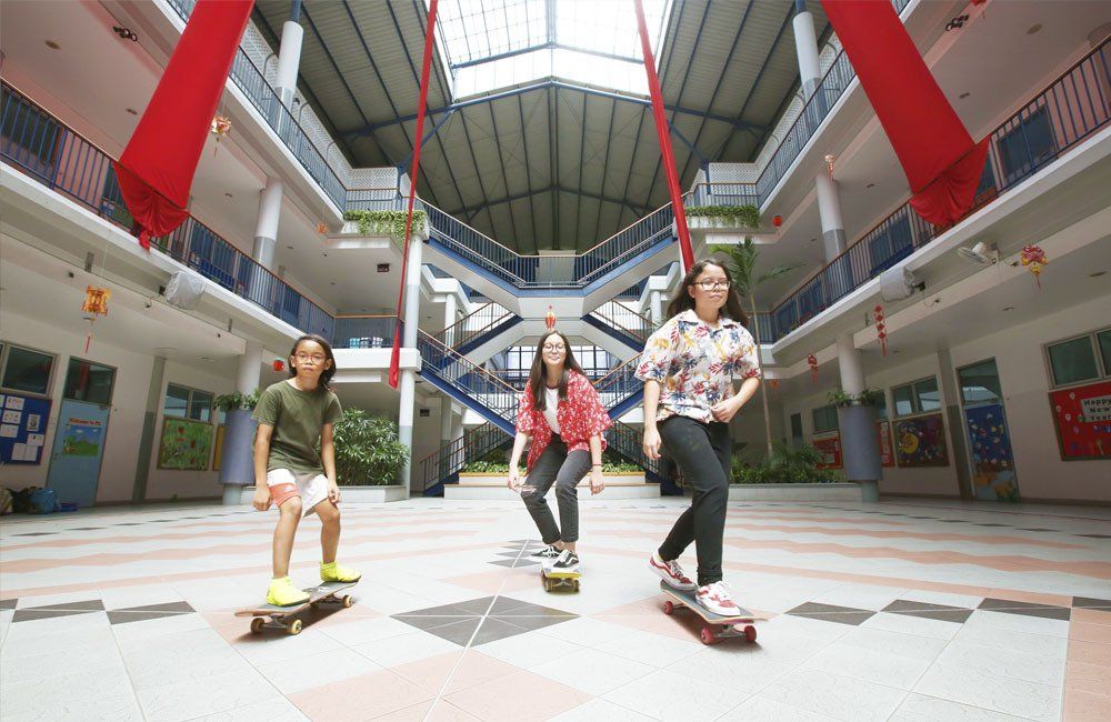Three girls are riding skateboards in a large building
