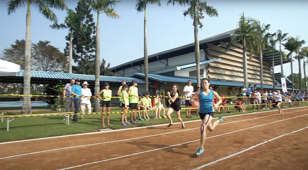 A group of people are running on a track in front of a building.