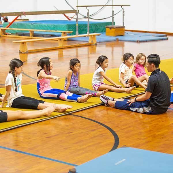 A group of children are sitting on the floor in a gym