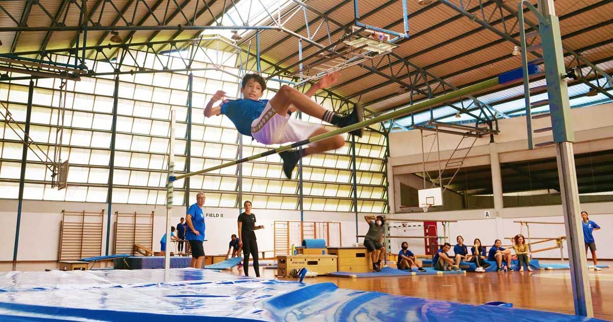 A young boy is doing a trick on a trampoline in a gym.