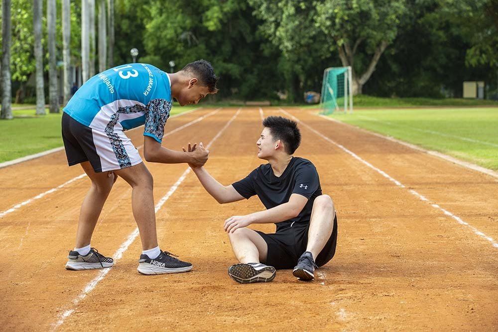 Two men are giving each other a high five on a track.