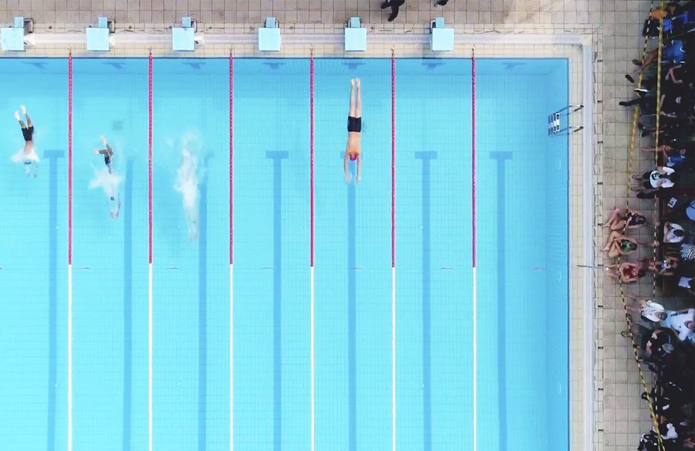 An aerial view of a swimming pool with people swimming in it.