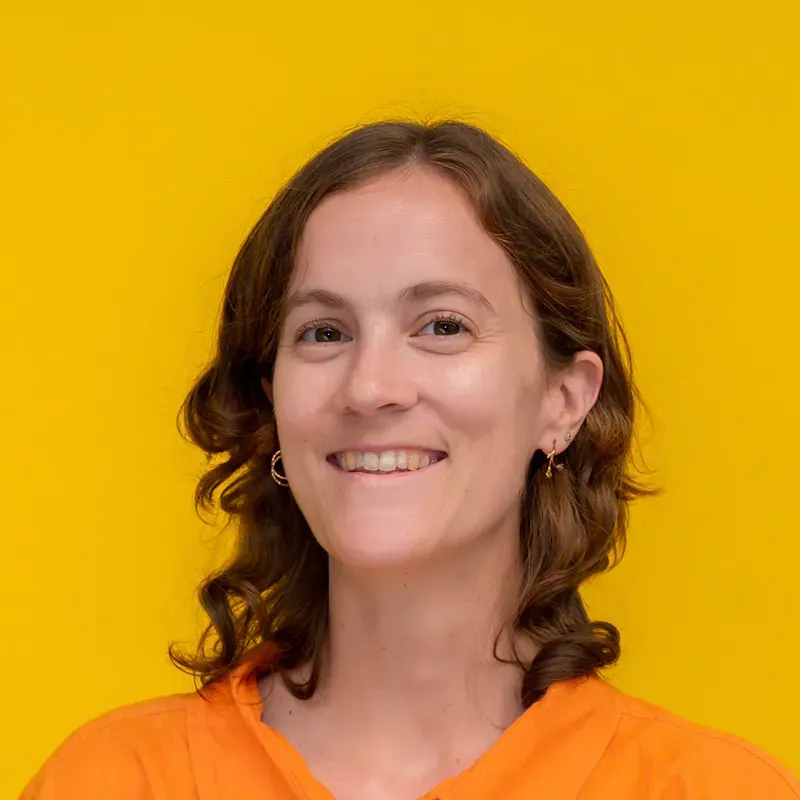 A woman in a blue striped shirt is smiling for the camera.