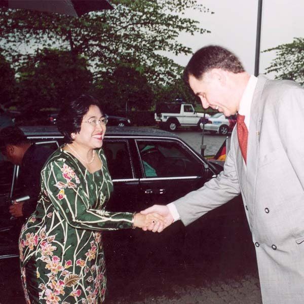 A woman in a green dress shakes hands with a man in a suit