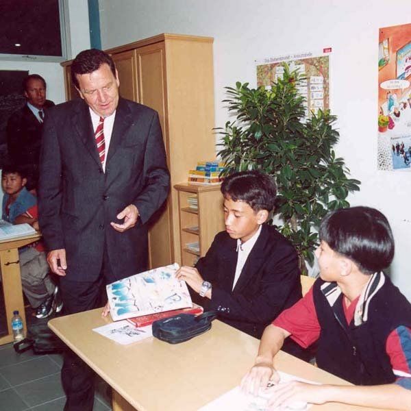 A man in a suit and tie is talking to a group of children