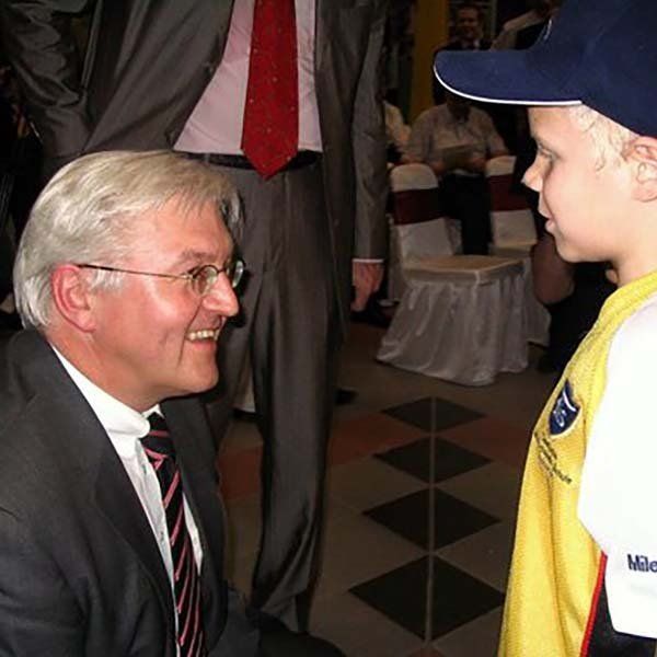 A man in a suit and tie is talking to a young boy