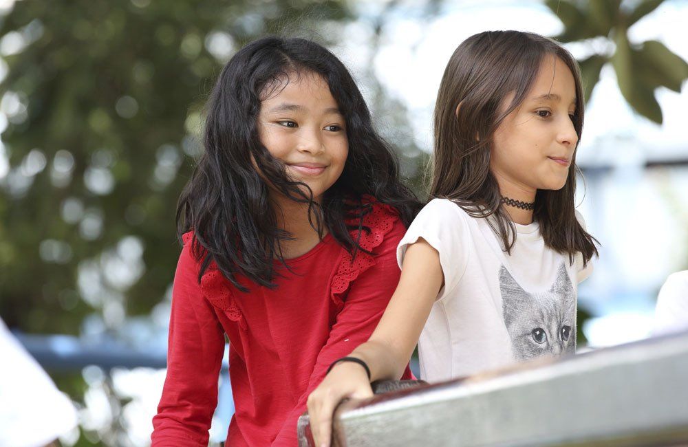 Two young girls are sitting next to each other on a slide.