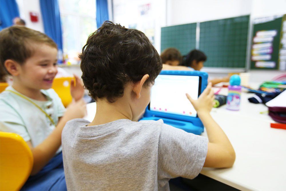 A young boy is using a tablet computer in a classroom.