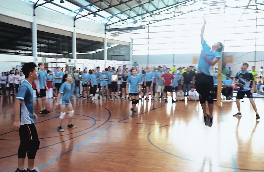 A group of people are playing volleyball in a gym.
