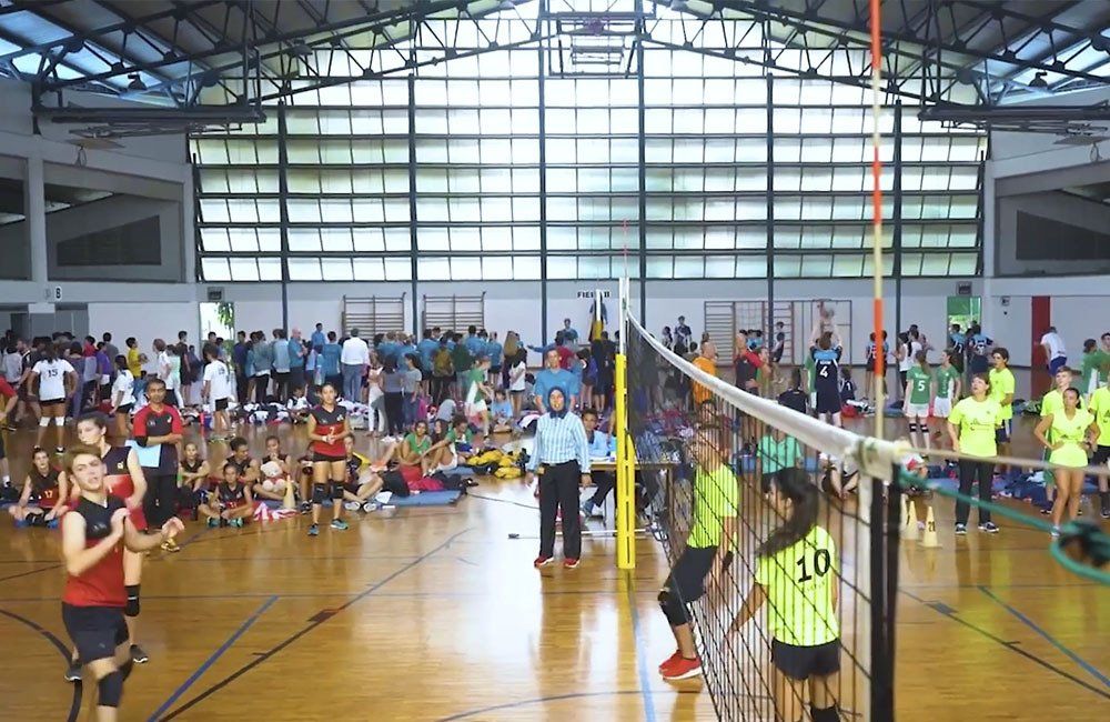 A group of people are playing volleyball in a large gym