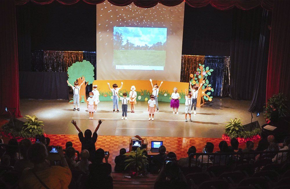 A group of children are dancing on a stage in front of a crowd.