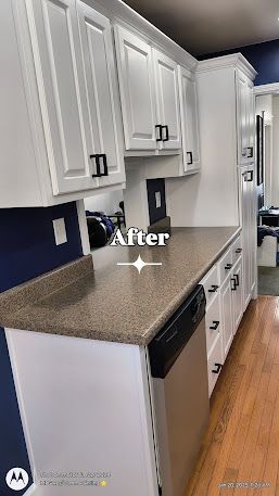 Bright remodeled galley kitchen with white cabinets, speckled countertops, dark blue walls, and wood floors.