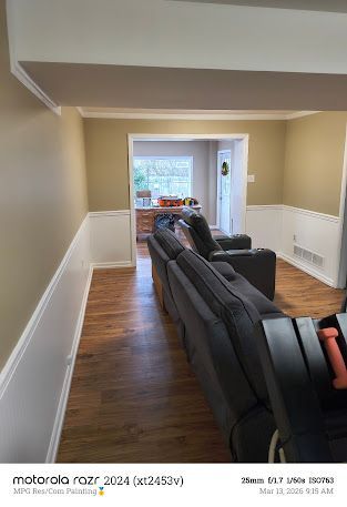 Living room with dark recliners, wood floor, cream walls, and French doors to a bright patio