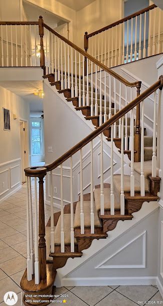 Interior staircase with white balusters, dark wood handrails, and cream walls in a foyer