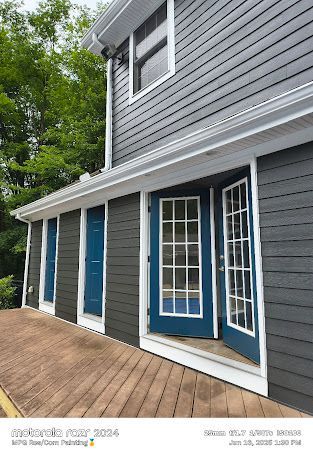 Gray two-story house exterior with blue front doors and white trim, viewed from the deck side
