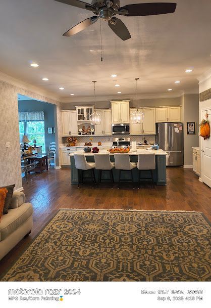 Open-plan kitchen and living room with island seating, stainless appliances, and warm wood floors