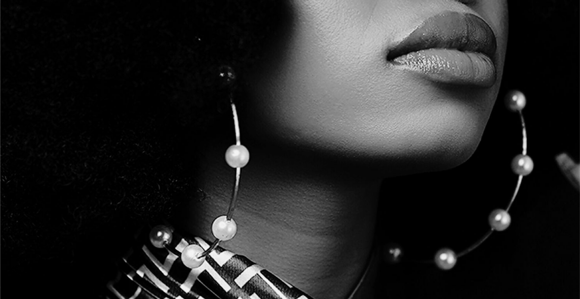 A black and white photo of a woman wearing pearl earrings.