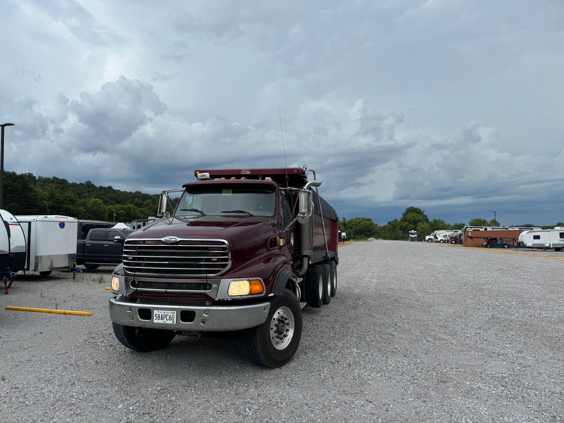 A red dump truck is parked in a gravel lot