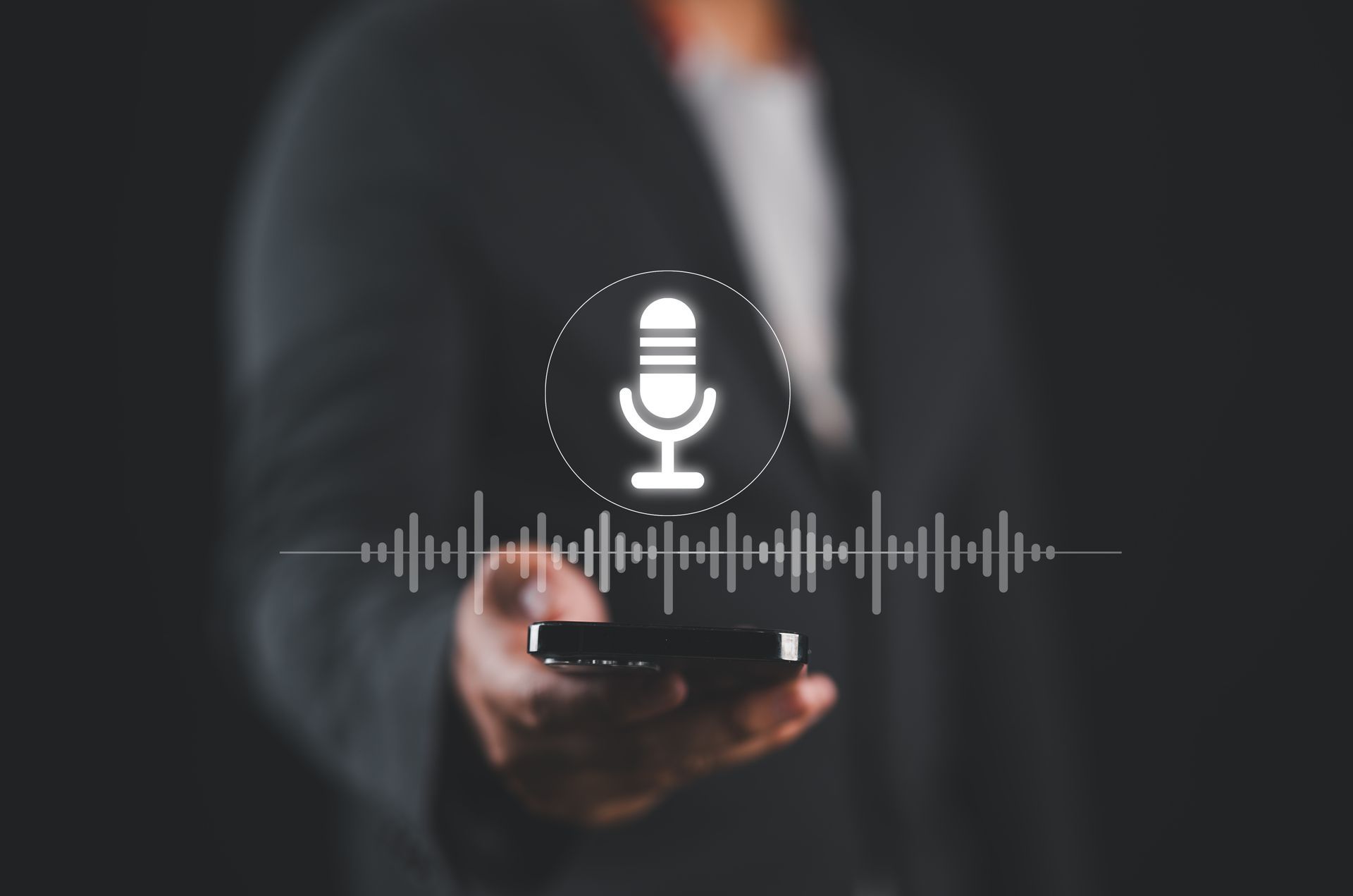 A man is holding a cell phone with a microphone icon on it.