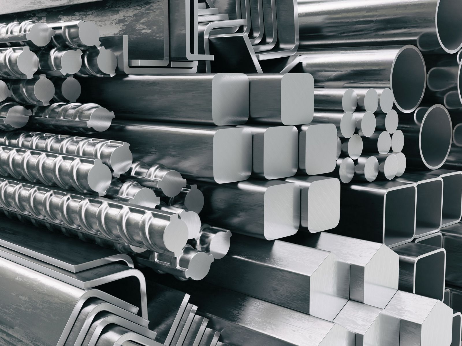 Assorted steel beams, rods, and pipes of various shapes stacked together, reflecting light.