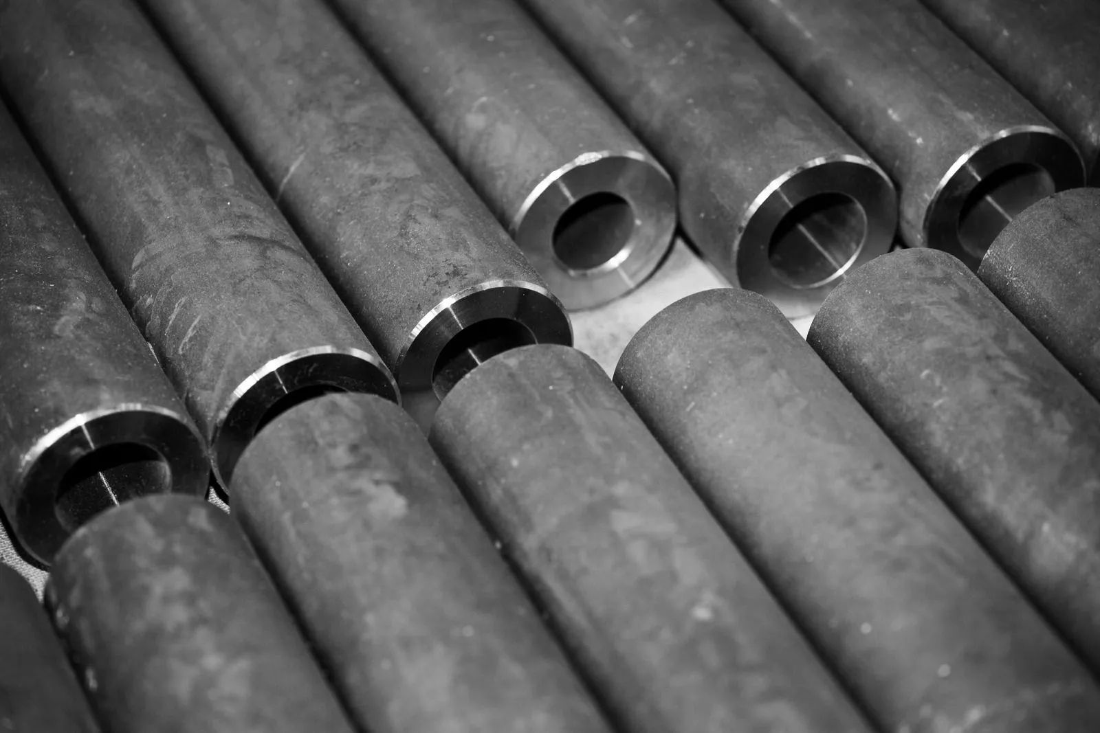 Stacked metal pipes with open ends in a black-and-white industrial close-up