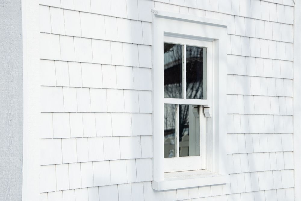 White window on white shingle siding.
