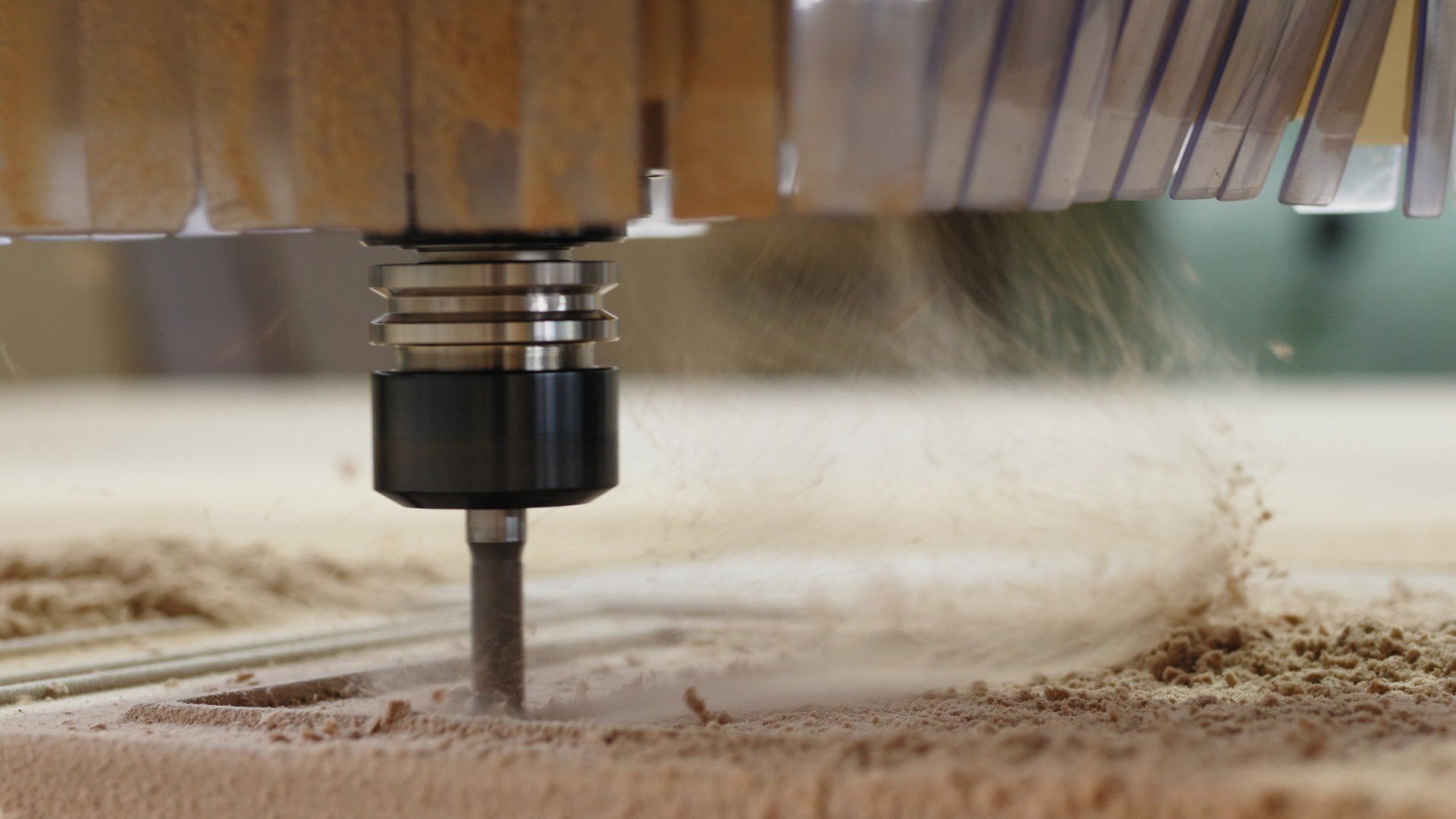 CNC router cutting wood, producing wood dust.