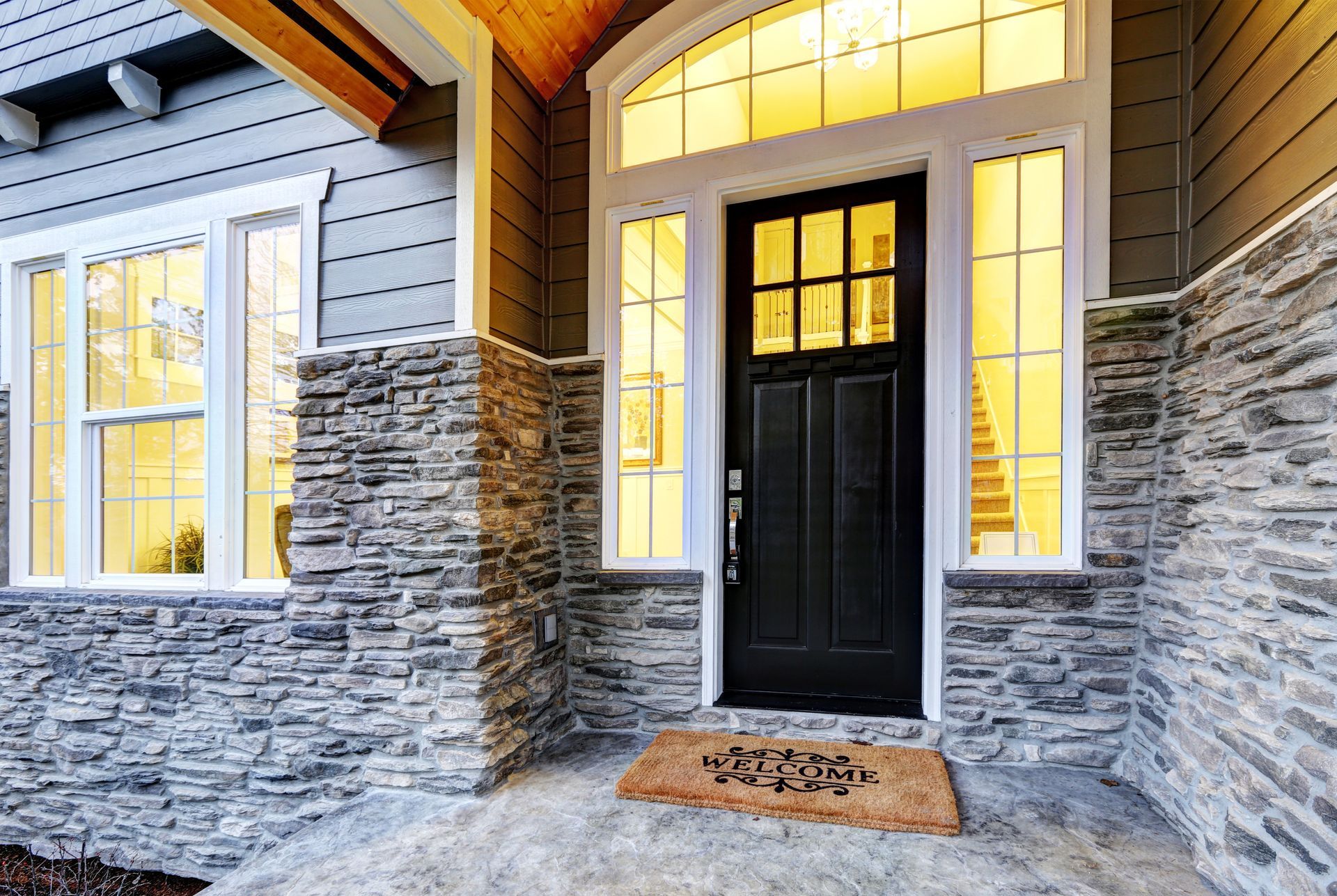 Black front door with sidelights and stonework on a home's entrance.
