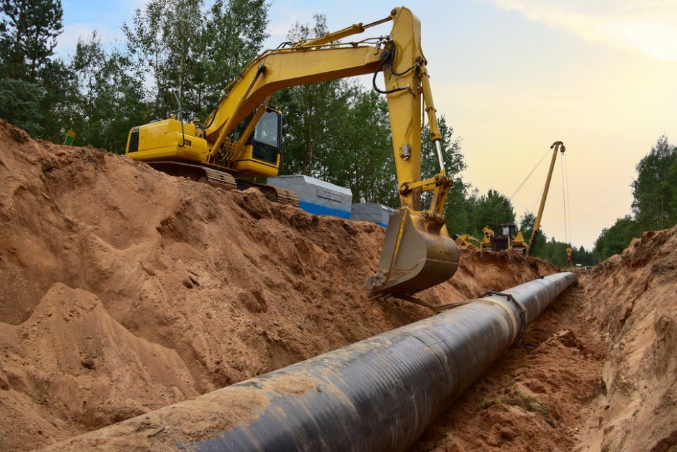 Yellow Excavator Over a Trench Laying Pipeline — Cairns Earthmoving Solutions In Redlynch, QLD