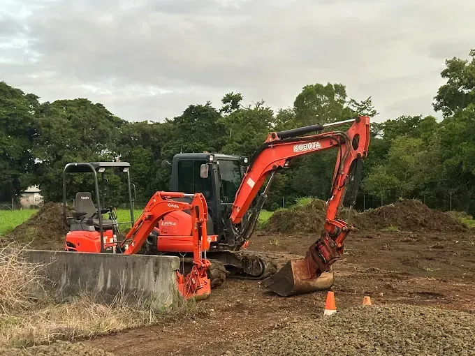 Two Red Excavator Dumping Dirt on a Construction Site — Cairns Earthmoving Solutions In Redlynch, QLD