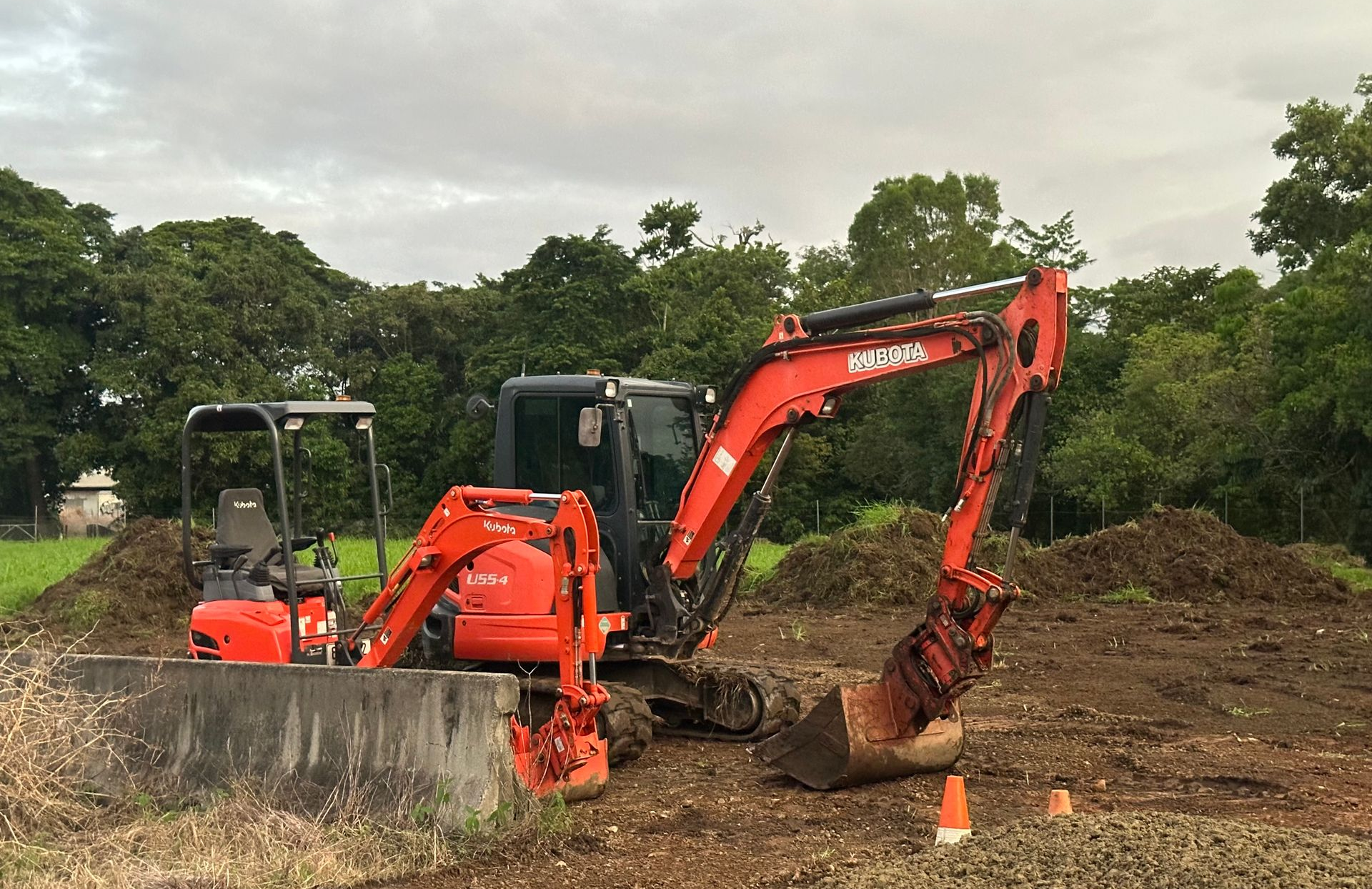 Red Backhoe Digging Into a Pile of Dirt Outdoors — Cairns Earthmoving Solutions In Gordonvale, QLD