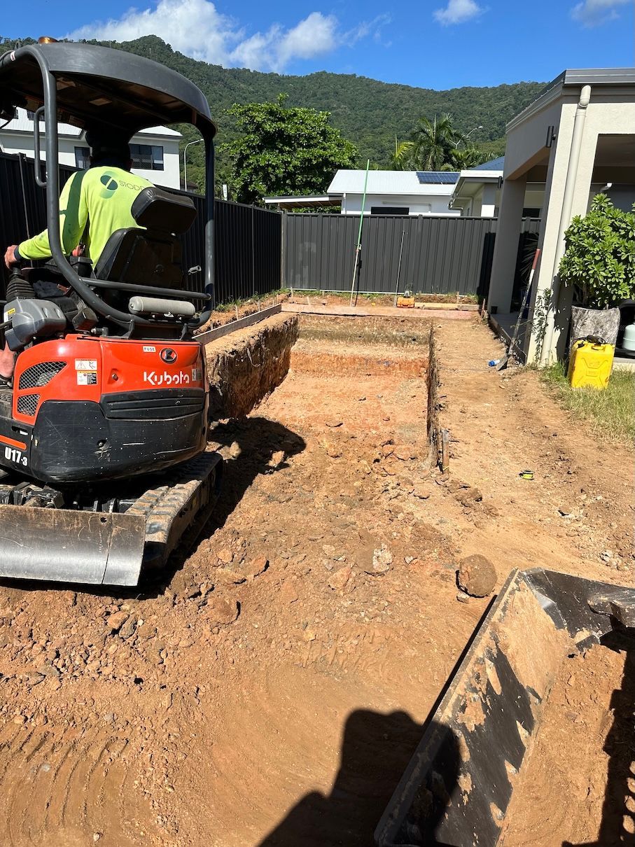 Red Excavator on a Pile of Rubble Under a Blue Sky — Cairns Earthmoving Solutions In Gordonvale, QLD