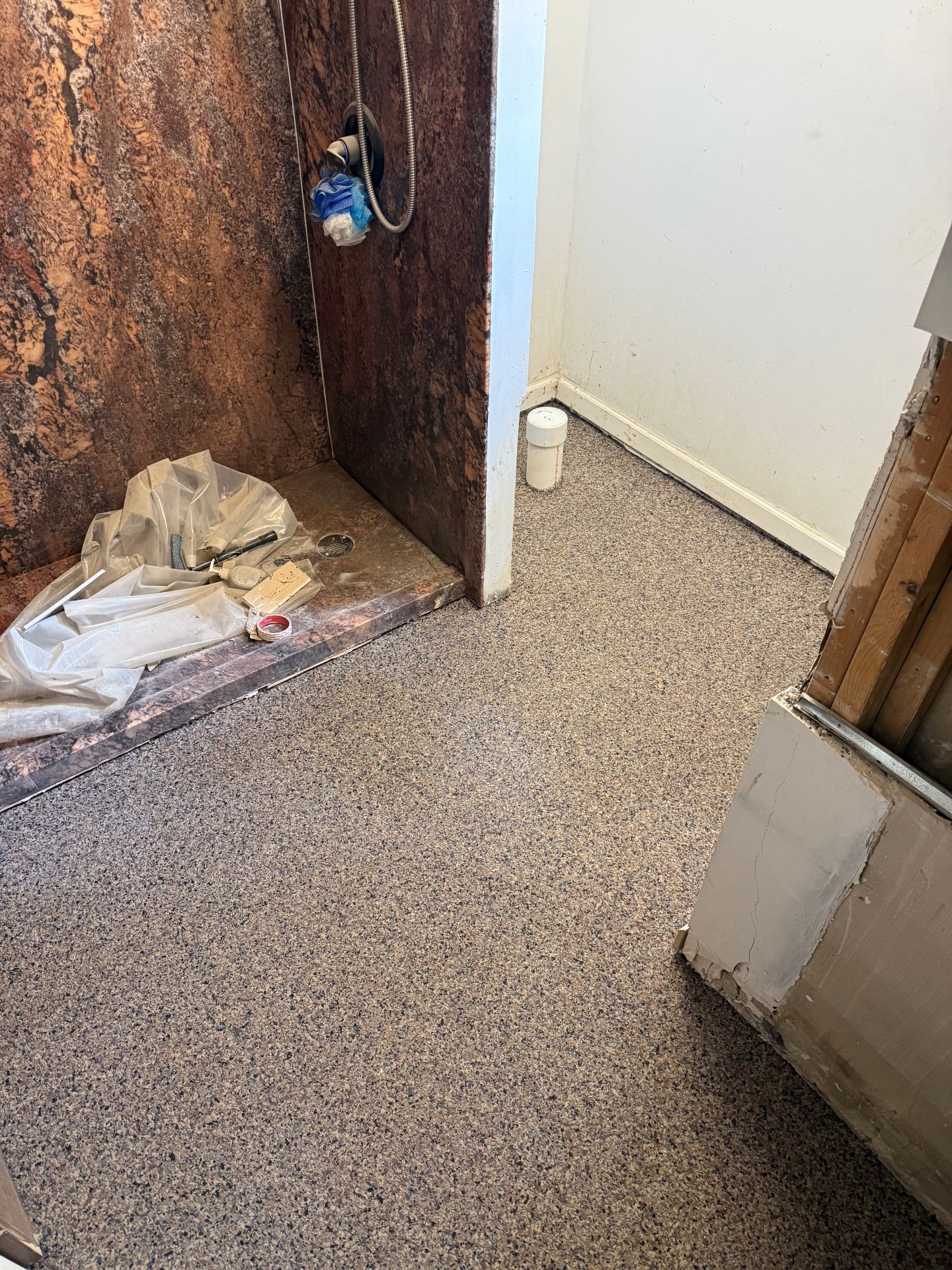 Rusty wall corner with a small blue fixture, trash on the floor, and a beige carpeted hallway.