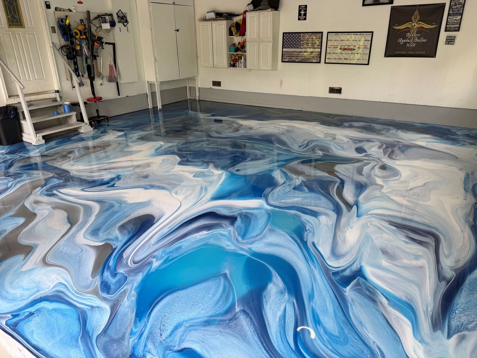 Swirling blue, white, and gray marbled epoxy floor in a room with wall plaques and equipment */}
