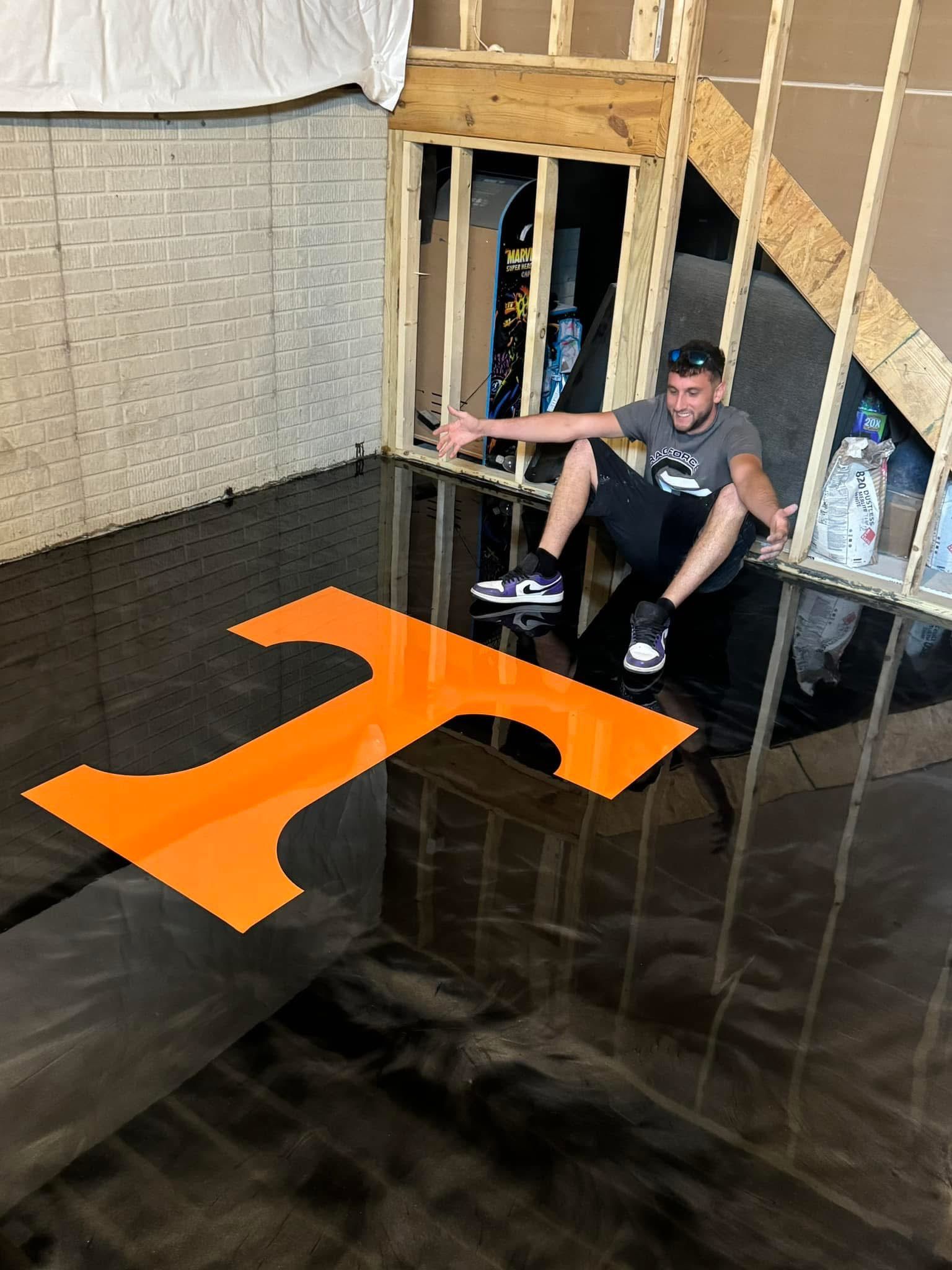 Person sitting beside unfinished stairs on a dark floor with an orange arrow marking direction.