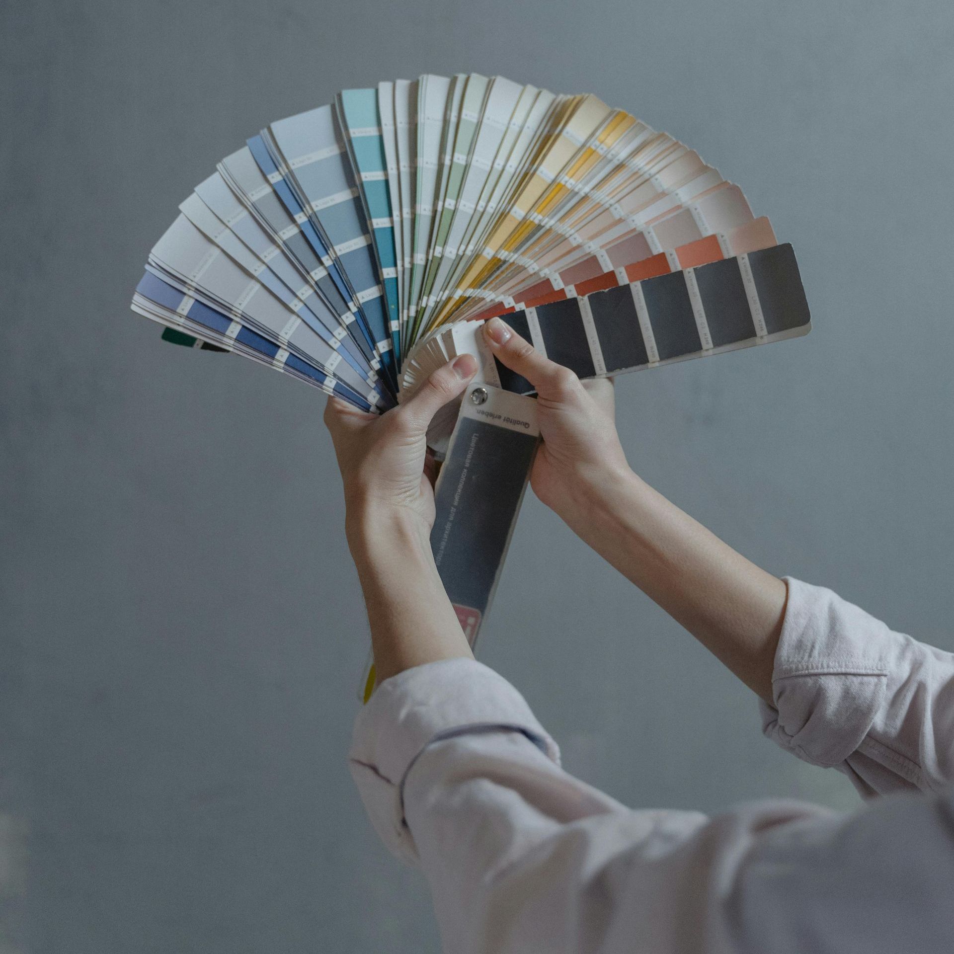 A person is holding a fan of paint samples in their hands